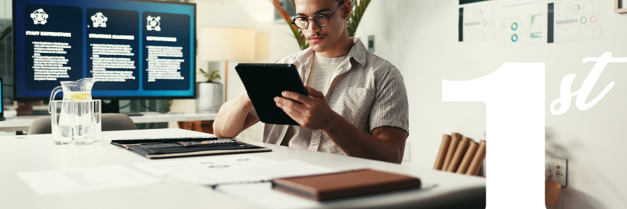 A man is sitting at a desk using a tablet computer.
