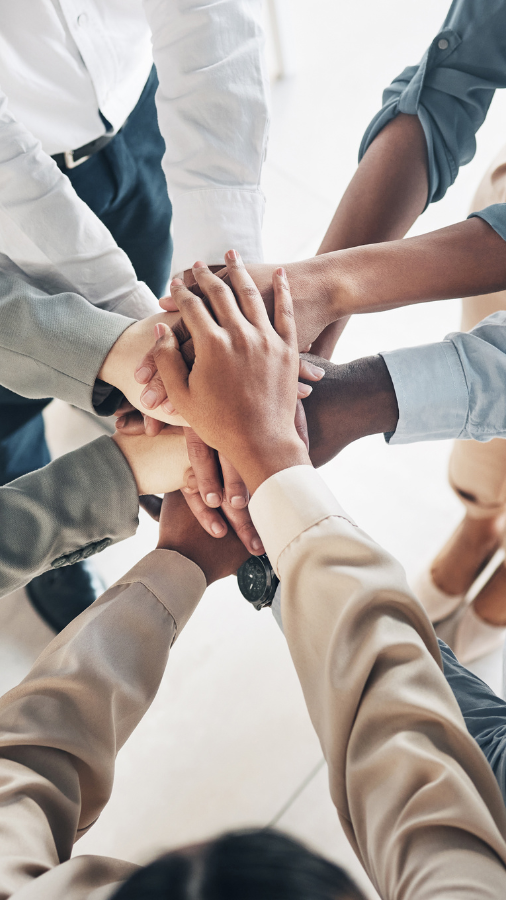 A group of people are putting their hands together in a circle.