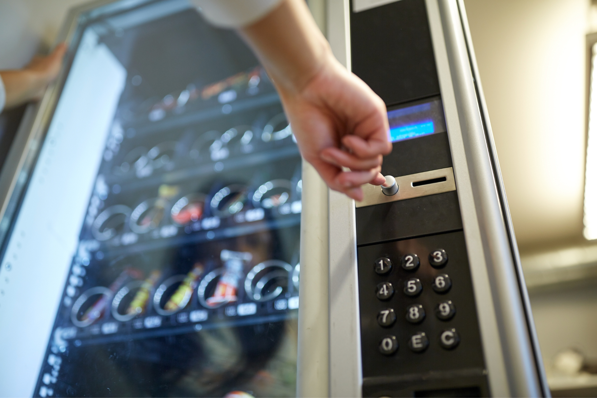 A person is inserting a coin into a vending machine