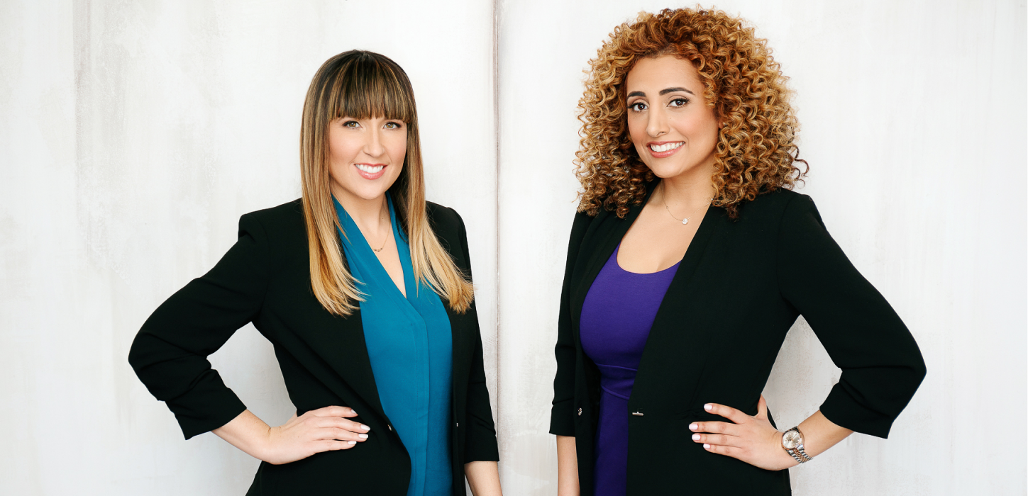 Two women are standing next to each other with their hands on their hips.