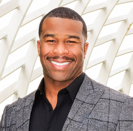 A man in a suit and black shirt is smiling for the camera