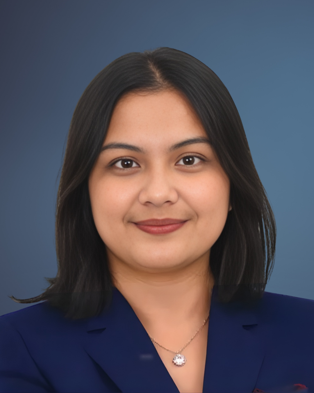 A woman wearing a blue jacket and a necklace smiles for the camera