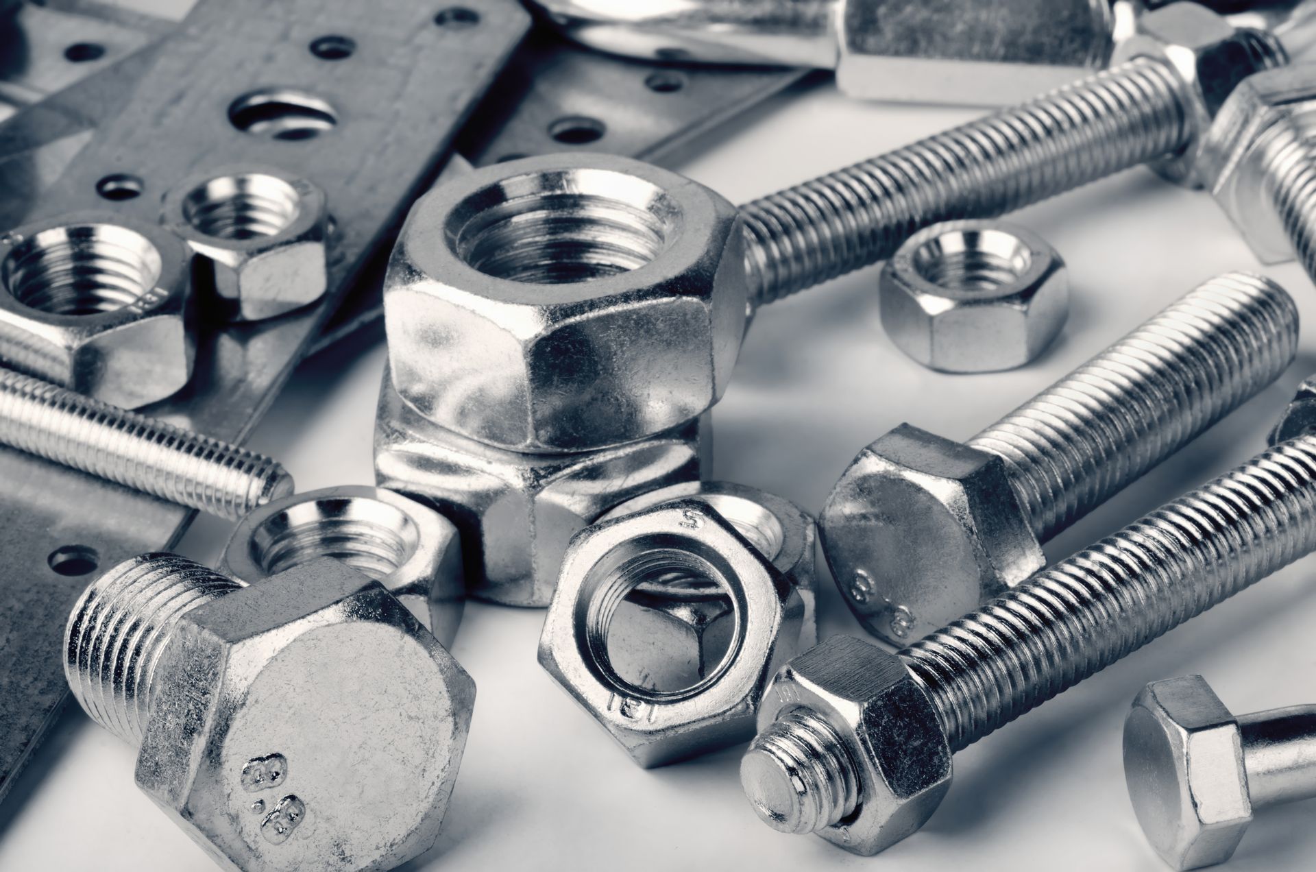 Close-up of various metal nuts, bolts, and plates, reflecting light.
