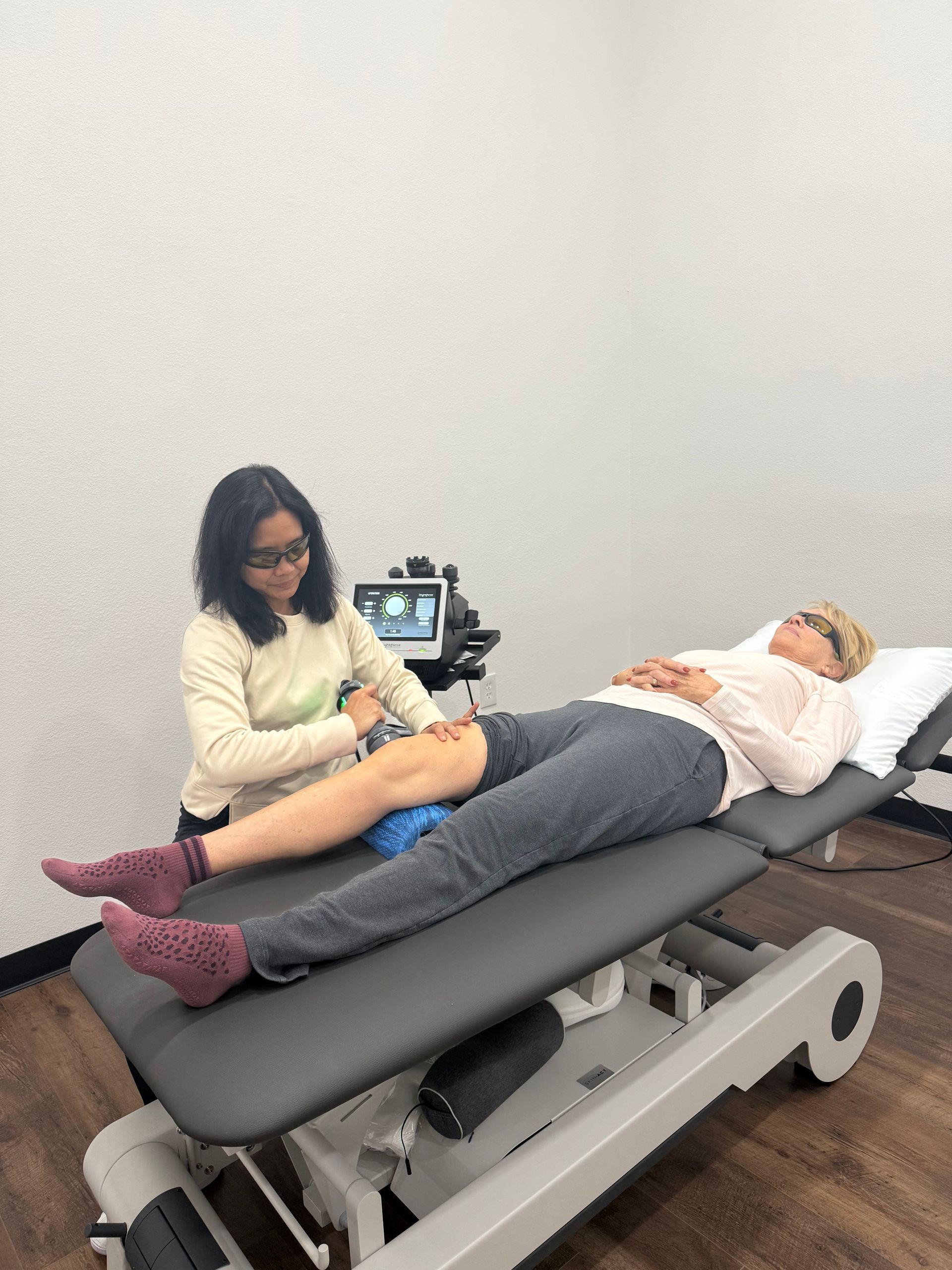 A woman is kneeling down while a doctor examines a patient 's foot.
