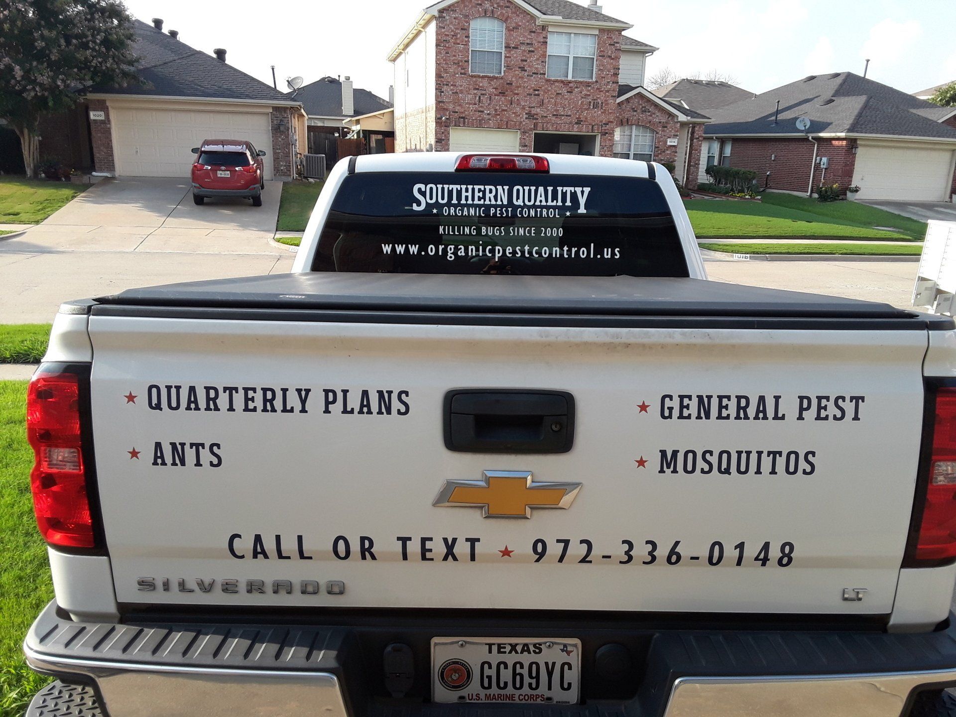 White Chevrolet Silverado truck with pest control services advertised on the tailgate.