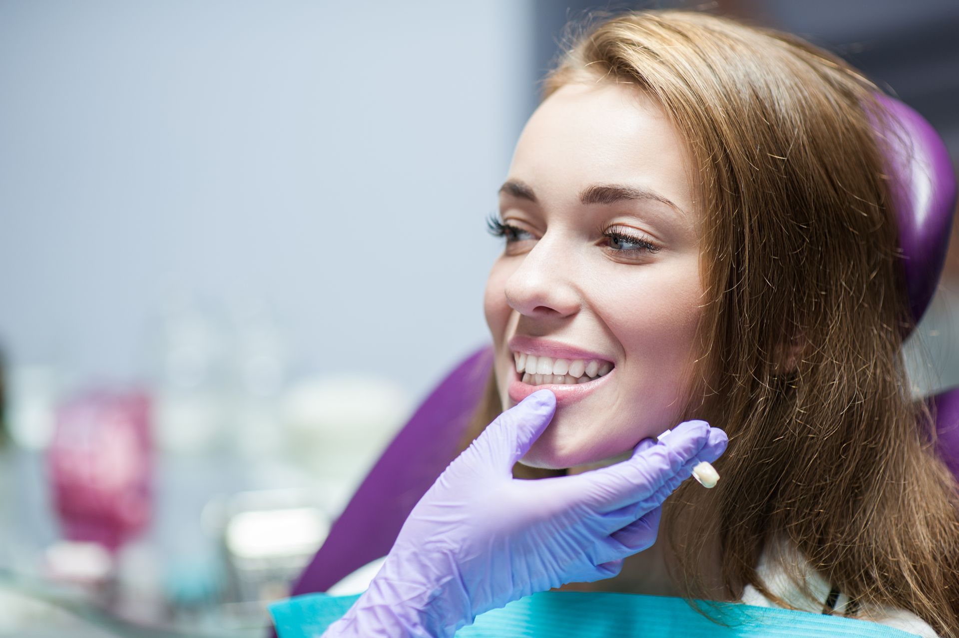 A smiling woman sitting in a dentist chair, ready for her dental crowns procedure. A smiling woman sitting in a dentist chair, ready for her dental crowns procedure.