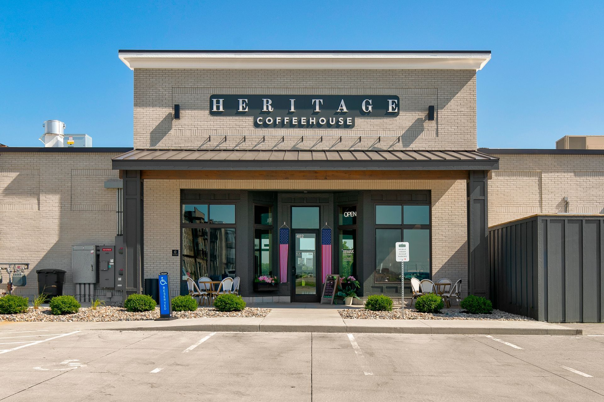 Front entrance of Heritage Coffeehouse with patio seating under a clear blue sky