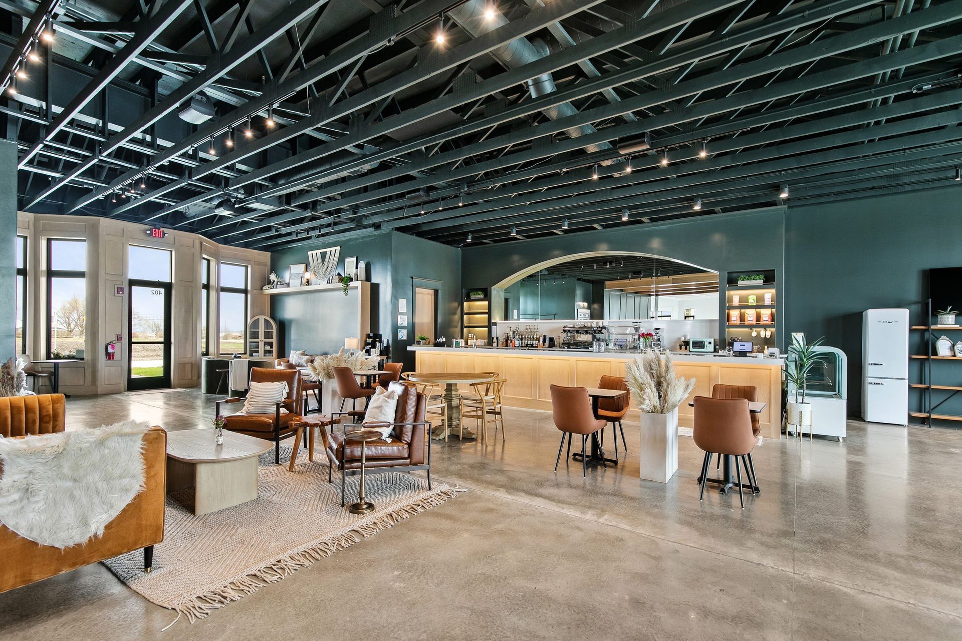 Spacious modern café interior with wood tables, tan chairs, and a dark open ceiling