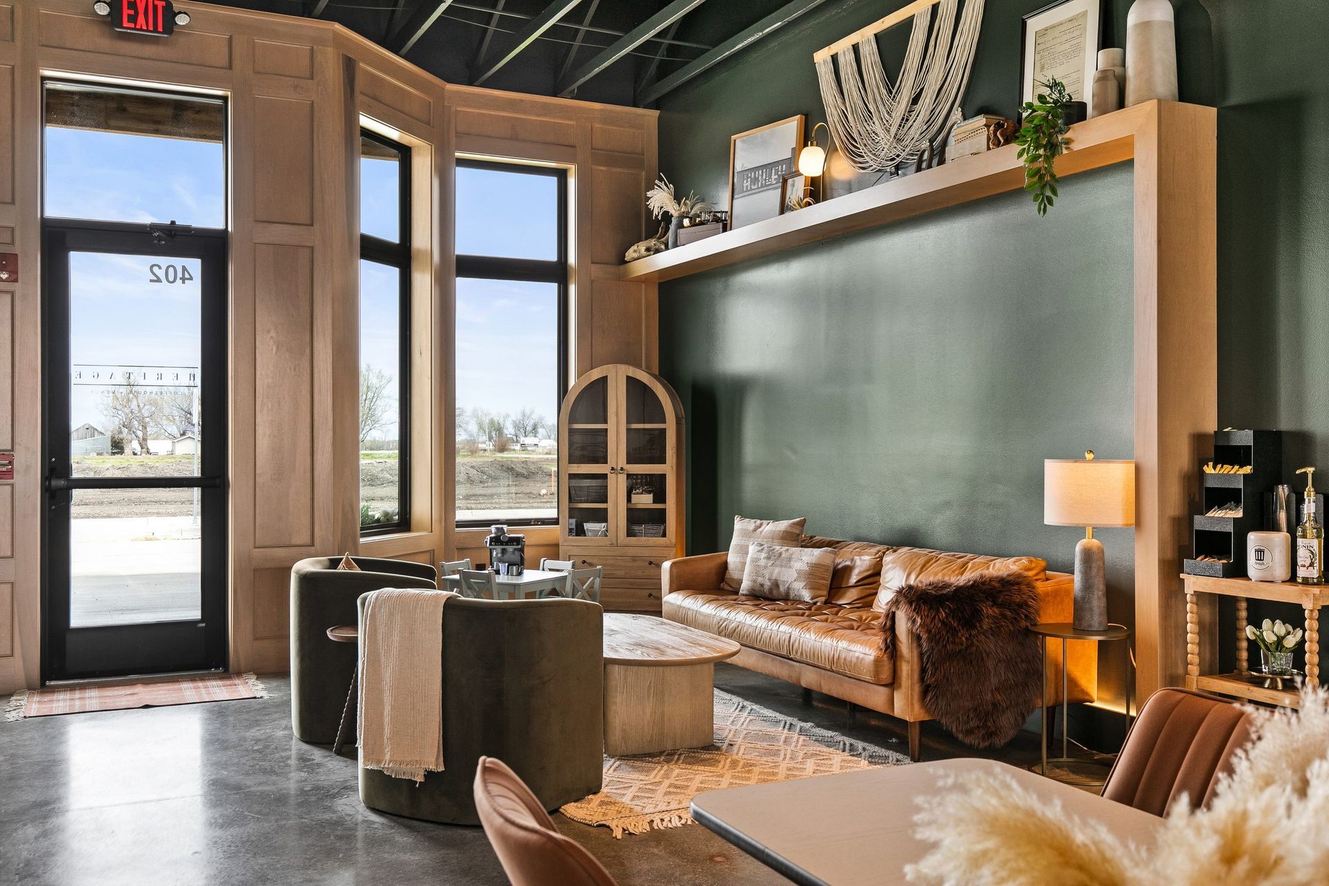 Stylish modern living room with brown sofa, fireplace, tall windows, and warm decor