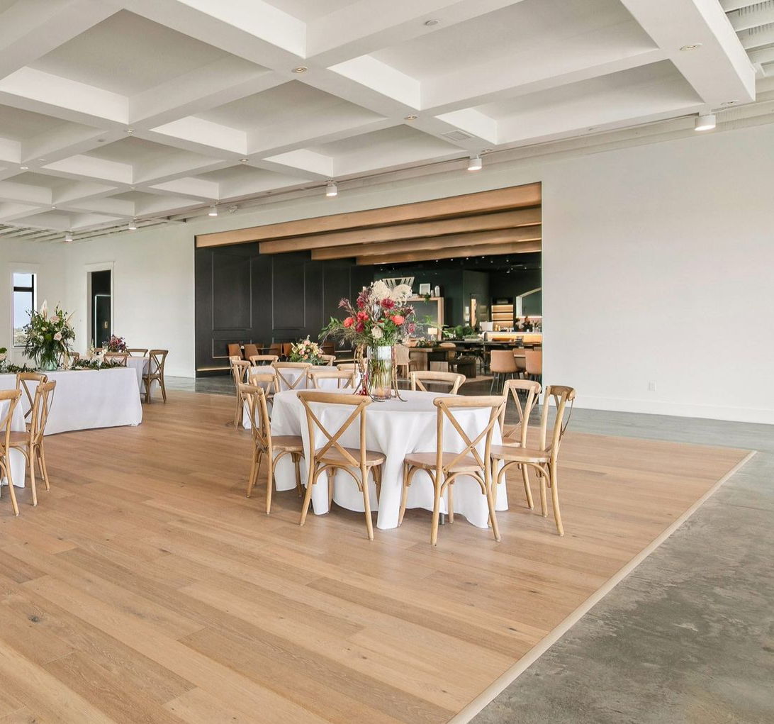 Bright loft event space with long white buffet table, large windows, and industrial garage doors