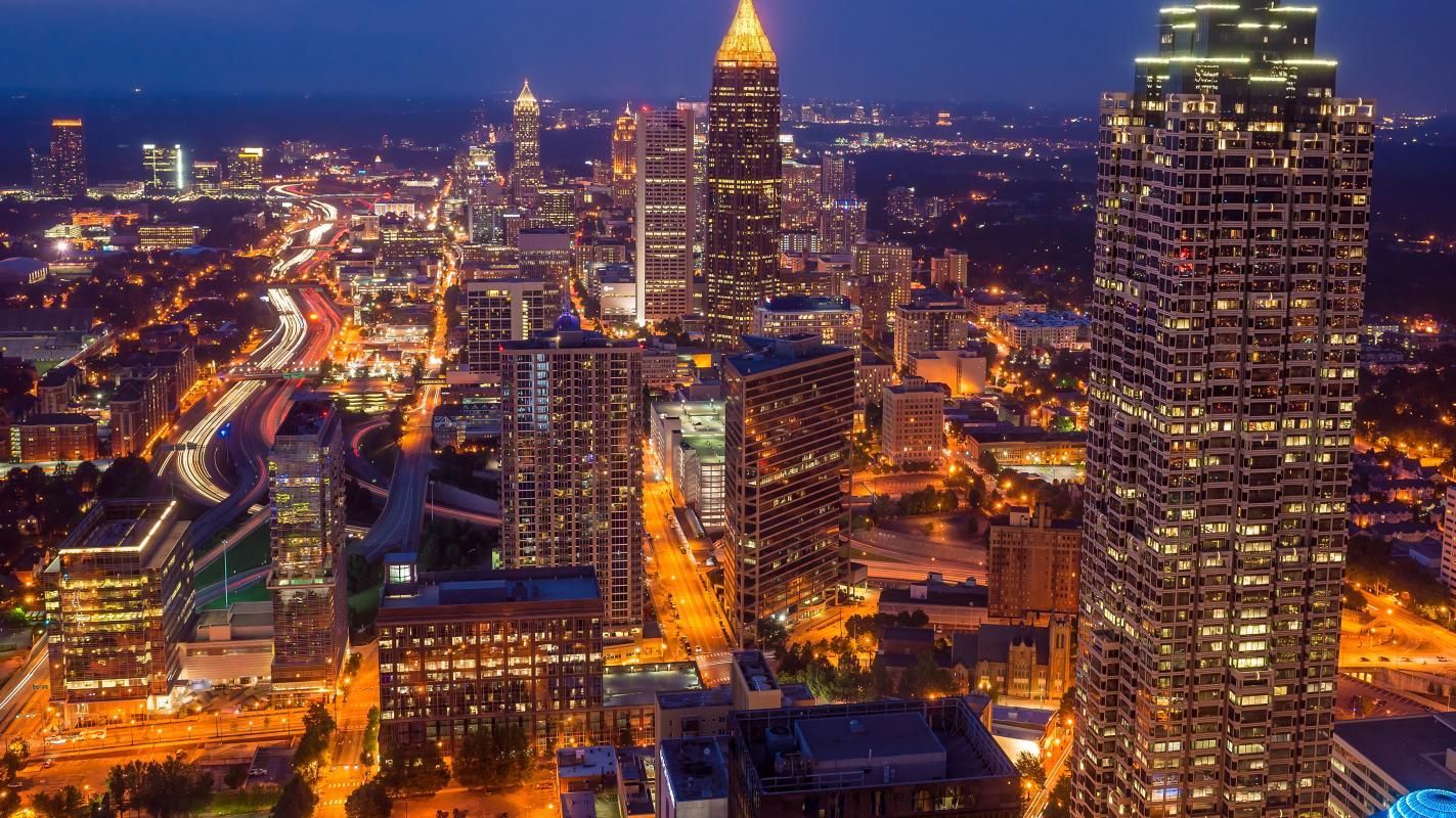 Nighttime cityscape of Atlanta, Georgia, with illuminated skyscrapers, buildings, and roadways.