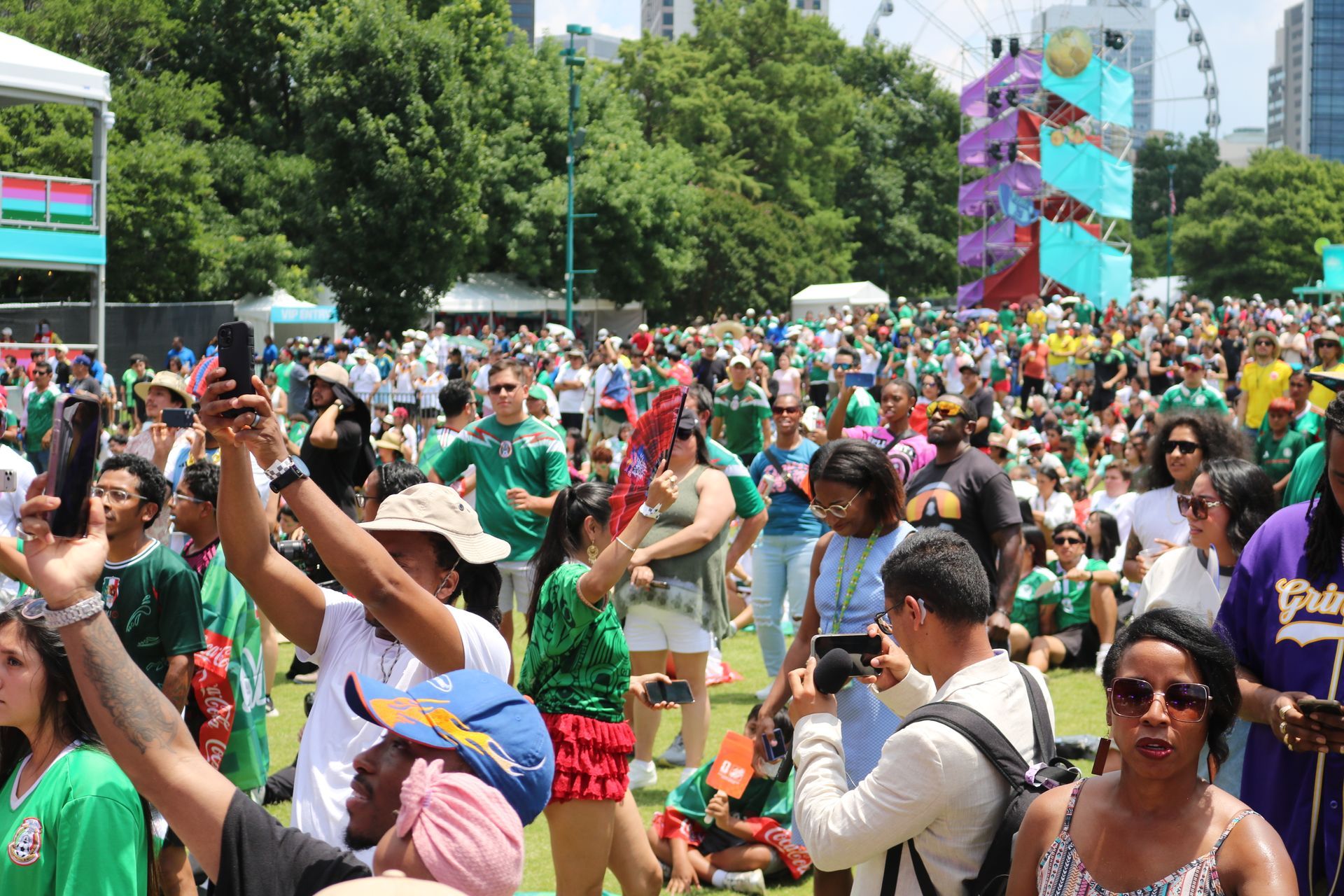 Crowd of people in colorful shirts celebrating at an outdoor festival in a city park
