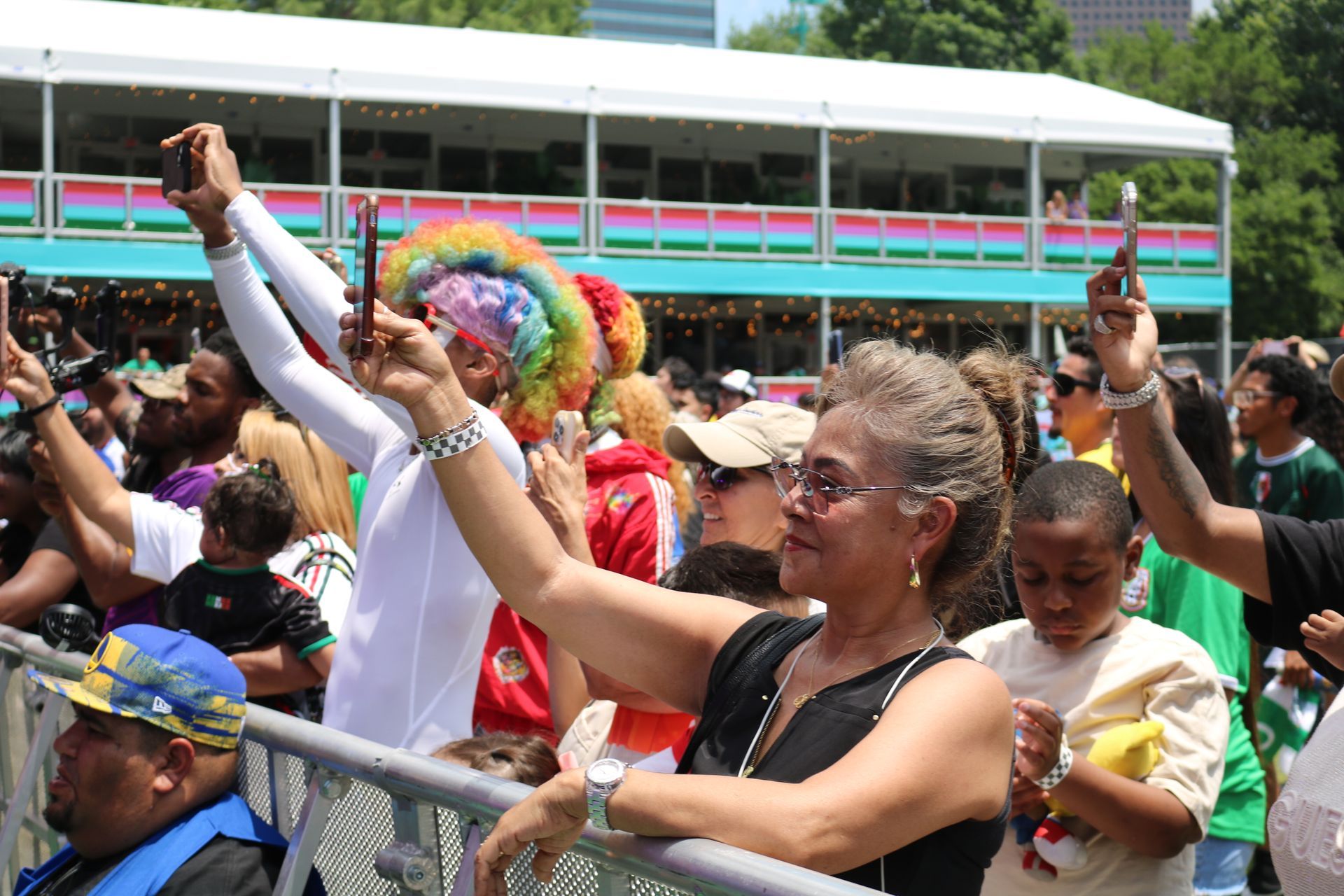Crowd cheering at a parade, with one woman raising her arm in front of a colorful float