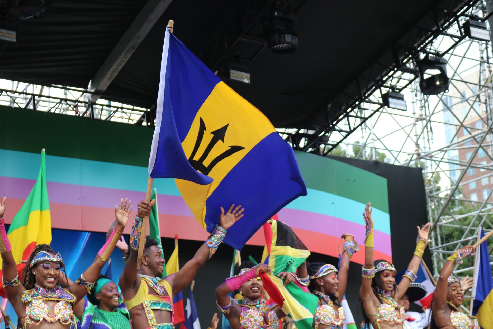 Crowd waving Barbados flags at a colorful outdoor stage event