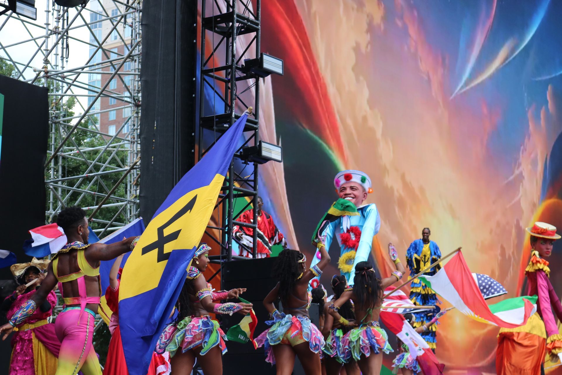 Colorful stage performance with dancers, flags, and bright abstract backdrop