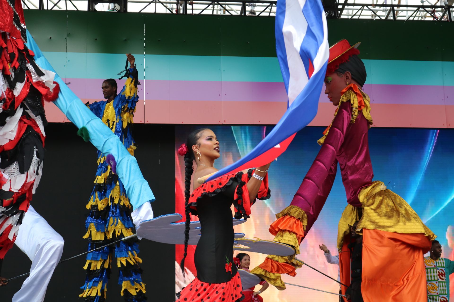 Colorful dancers performing with flowing ribbons on a stage backdrop with stripes