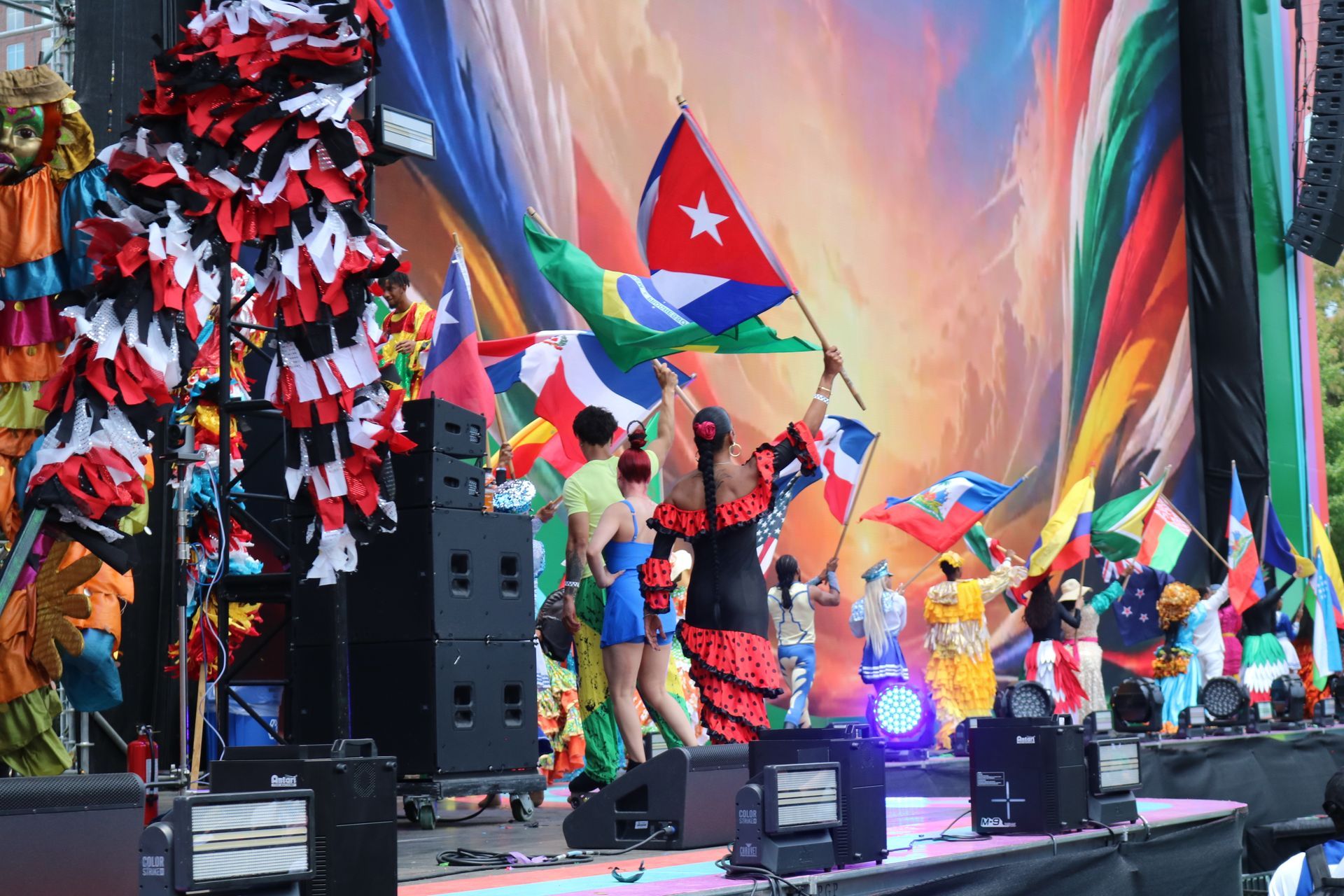 Colorful stage performance with dancers, Cuban flags, and bright fabric backdrops