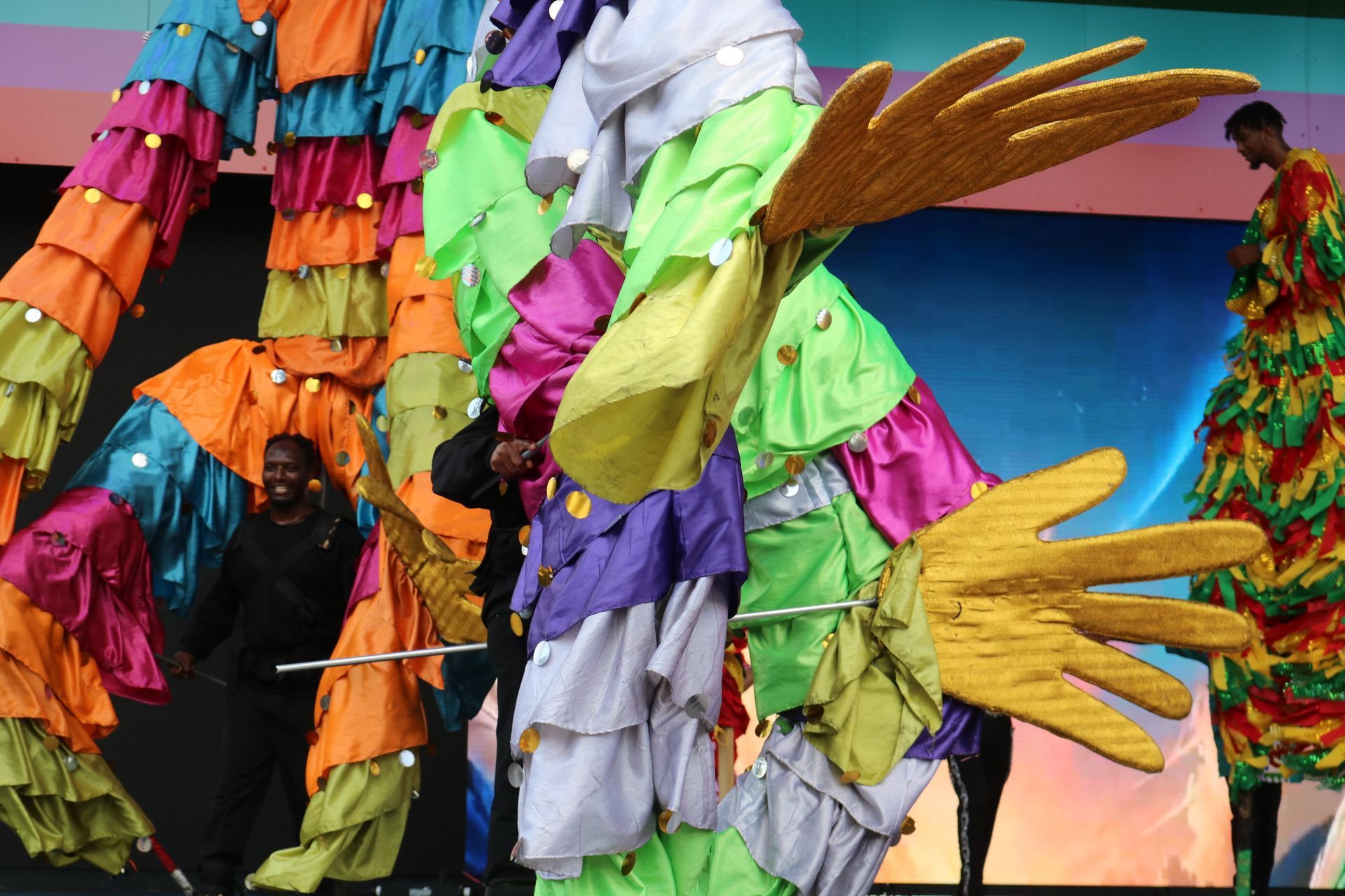 Colorful decorative hands and fabric on a carnival float with a sunset sky backdrop