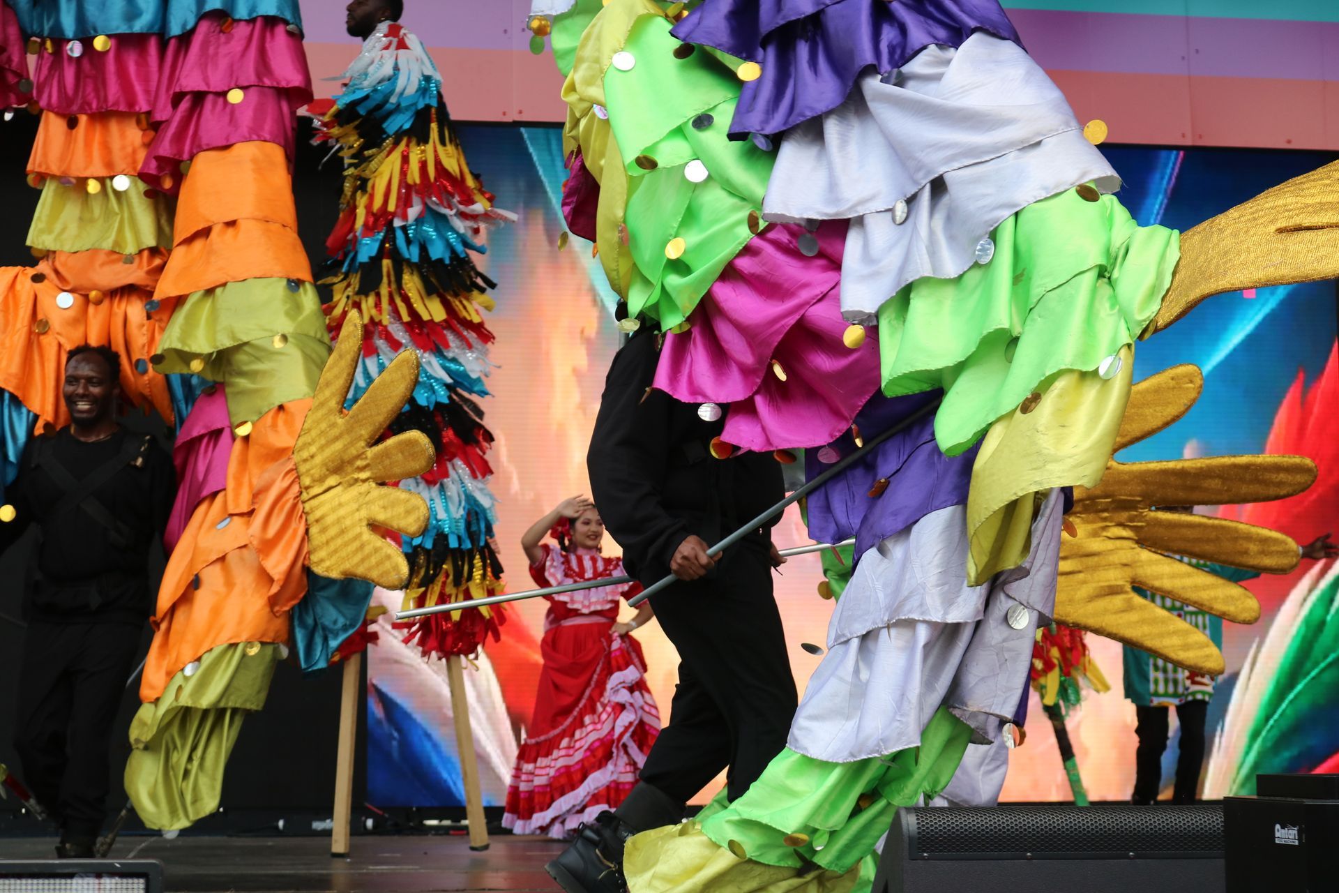 Colorful feathered costumes on stage with a central performer holding a microphone