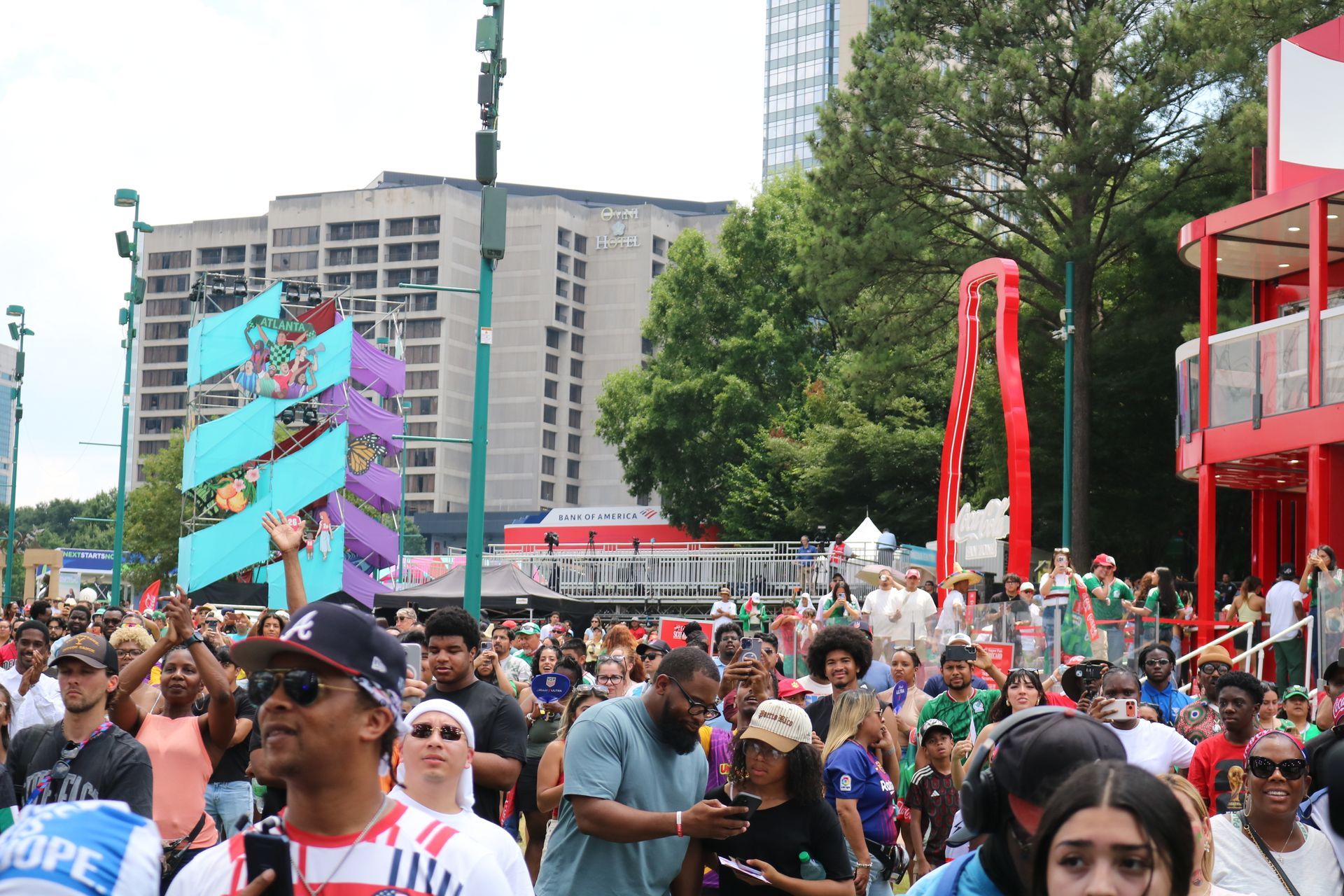 Crowded outdoor festival with colorful art installations, tents, and people walking in a city plaza