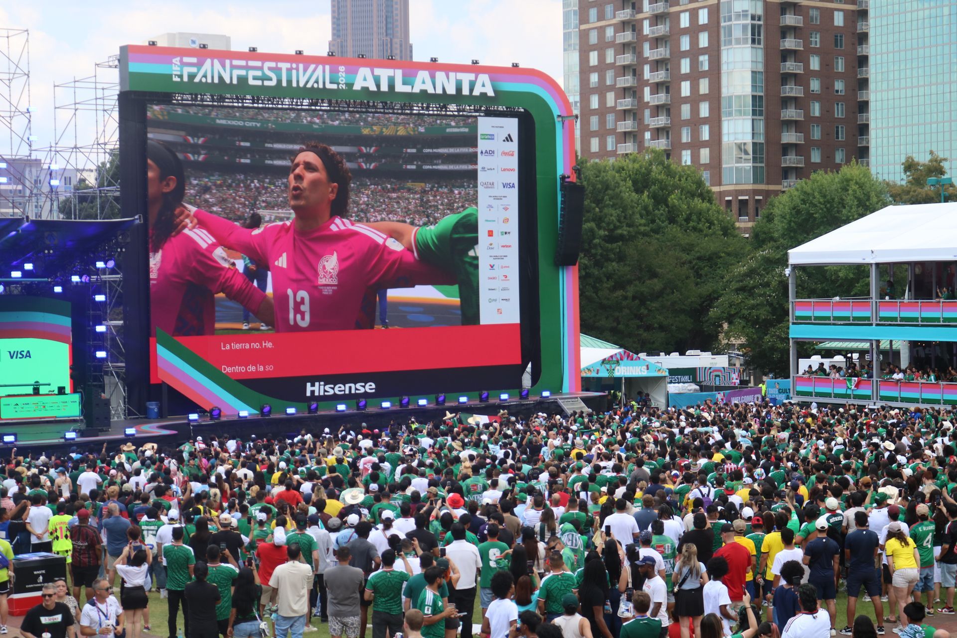 Crowd watching a soccer match on a giant screen at Fan Festival Atlanta, with a player in pink on display