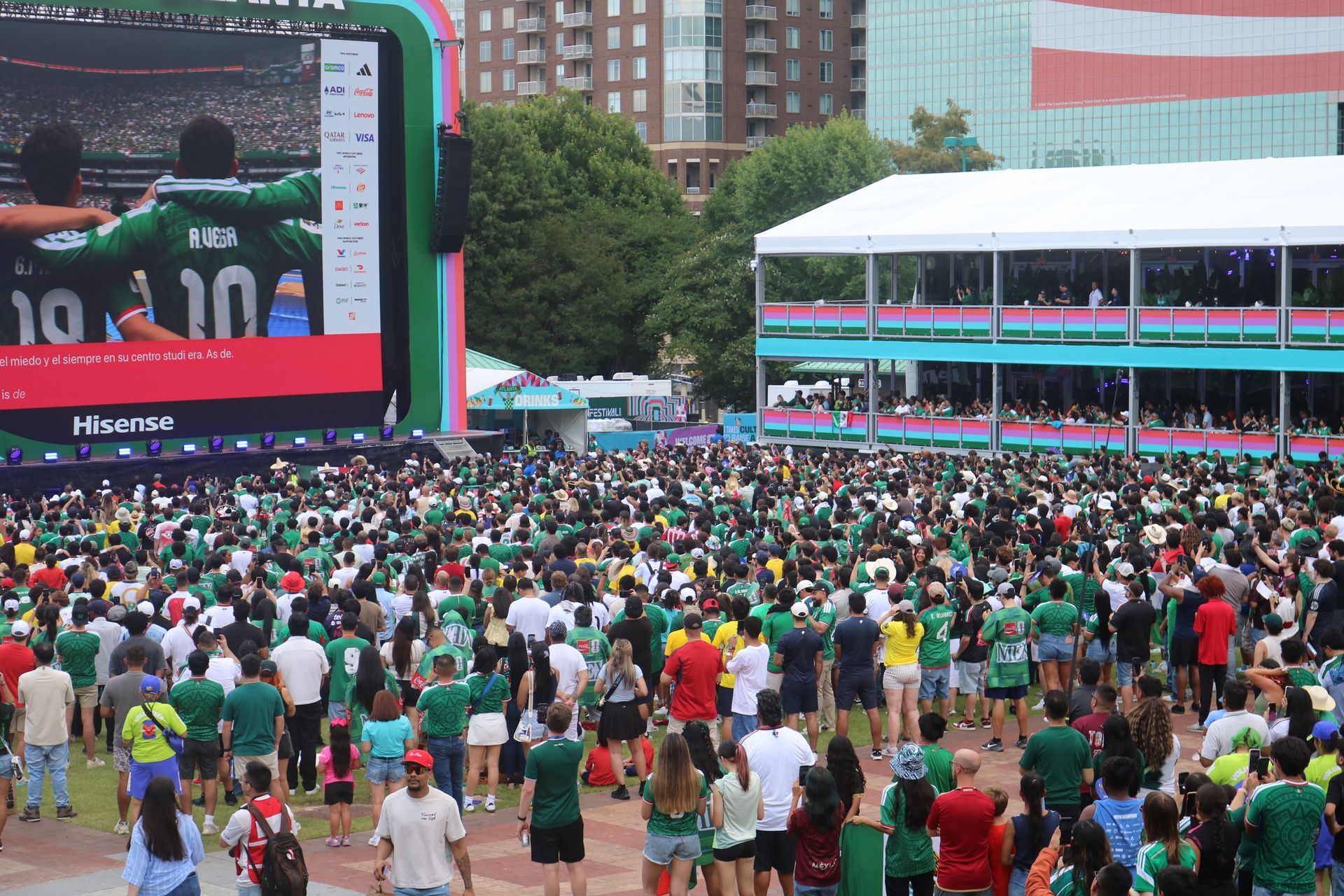 Crowd watching a soccer match on a giant outdoor screen at a fan event