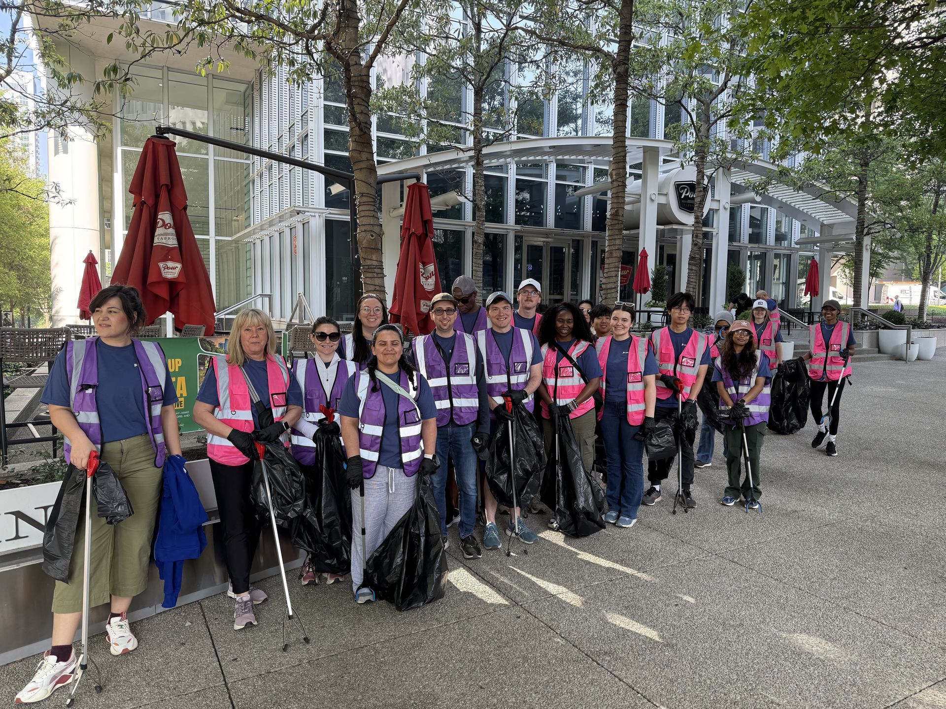 Group of people in pink and purple vests posing with walking poles outside a modern building