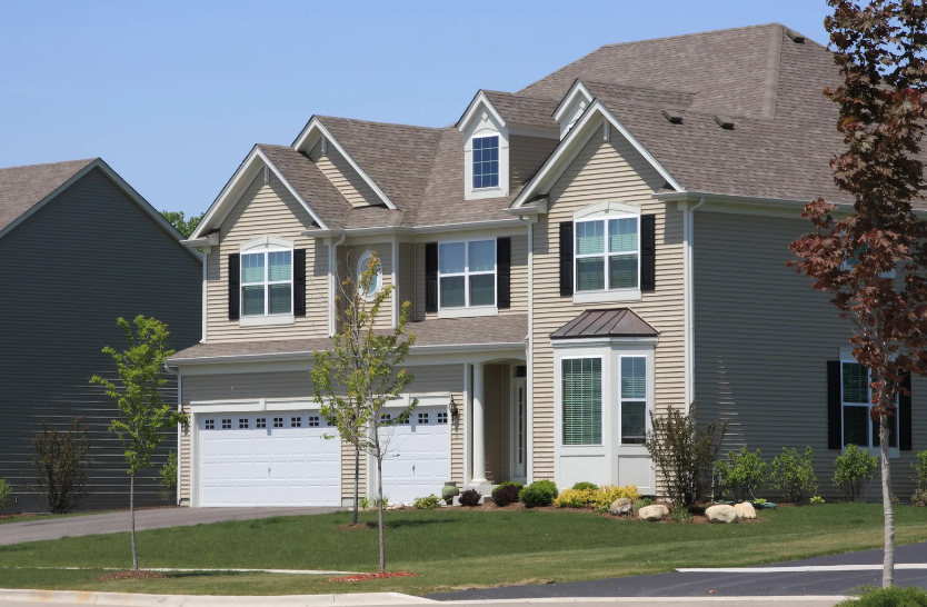A large house with a gray roof and white garage doors