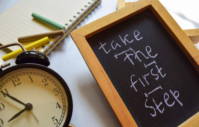 A chalkboard with the words take the first step written on it