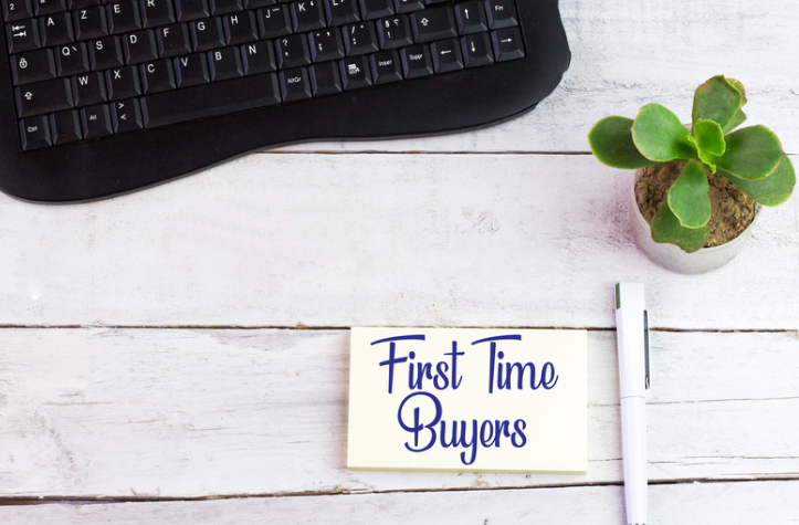 A sign that says first time buyers is on a wooden table next to a keyboard.
