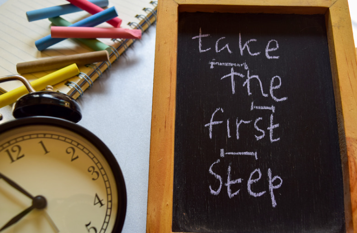 A chalkboard with the words take the first step written on it