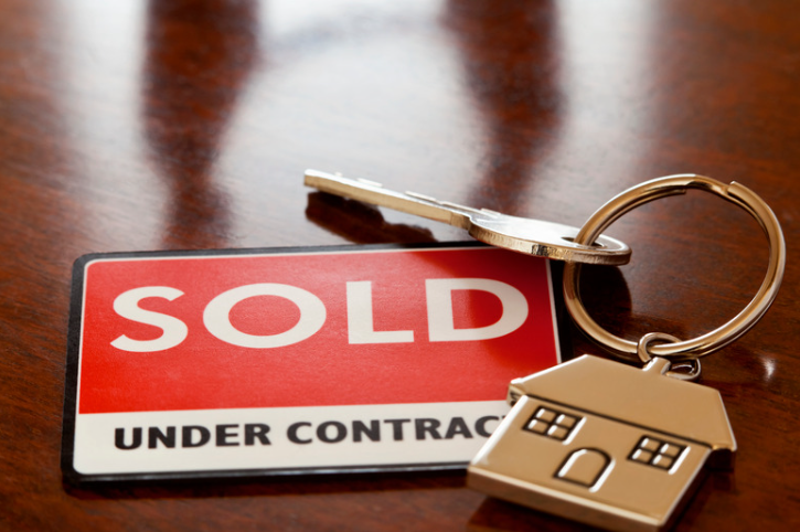 A sold under contract sign next to a key