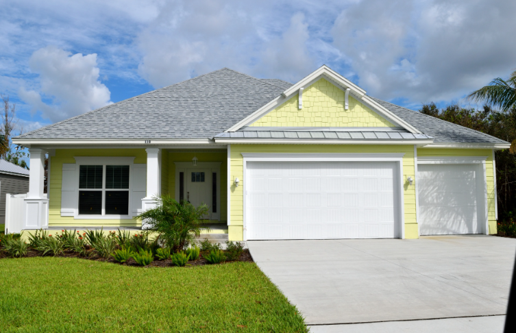 A yellow house with a white garage door and a gray roof