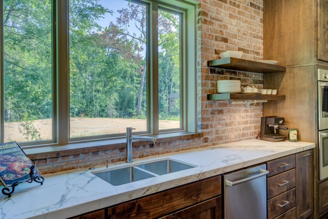 A kitchen with a sink , dishwasher , and large window.
