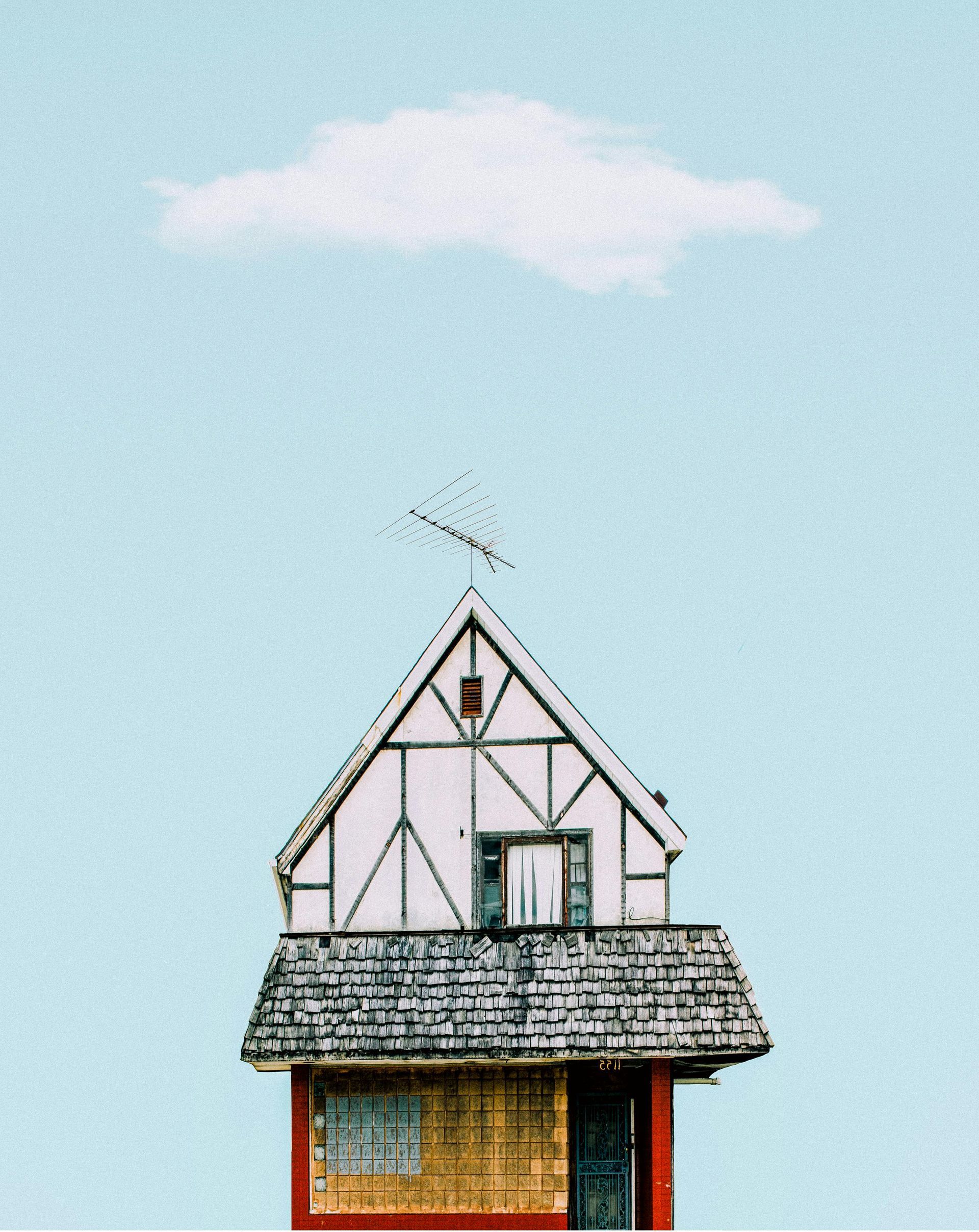 A small house with a cloud in the sky above it