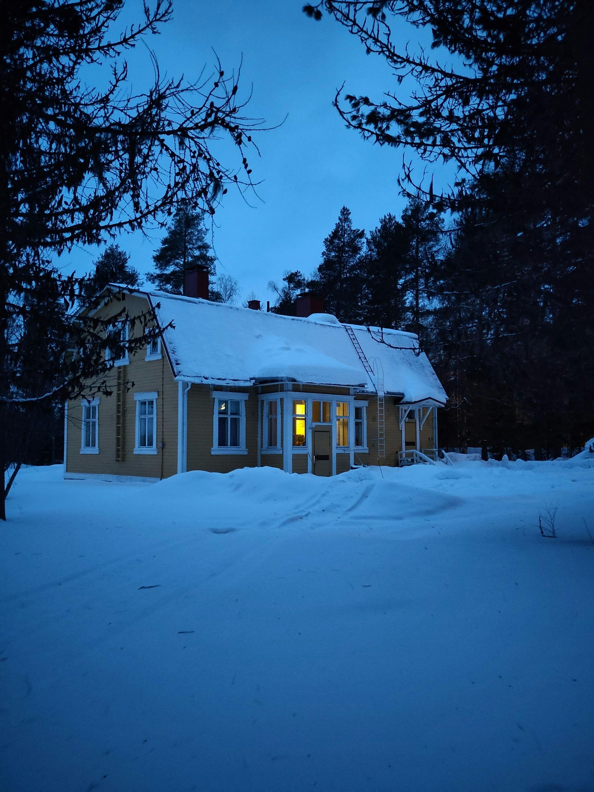 A house with snow on the roof is lit up at night