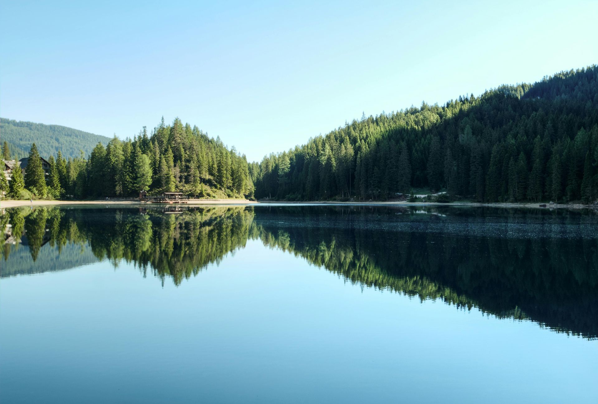 A lake surrounded by trees and mountains on a sunny day