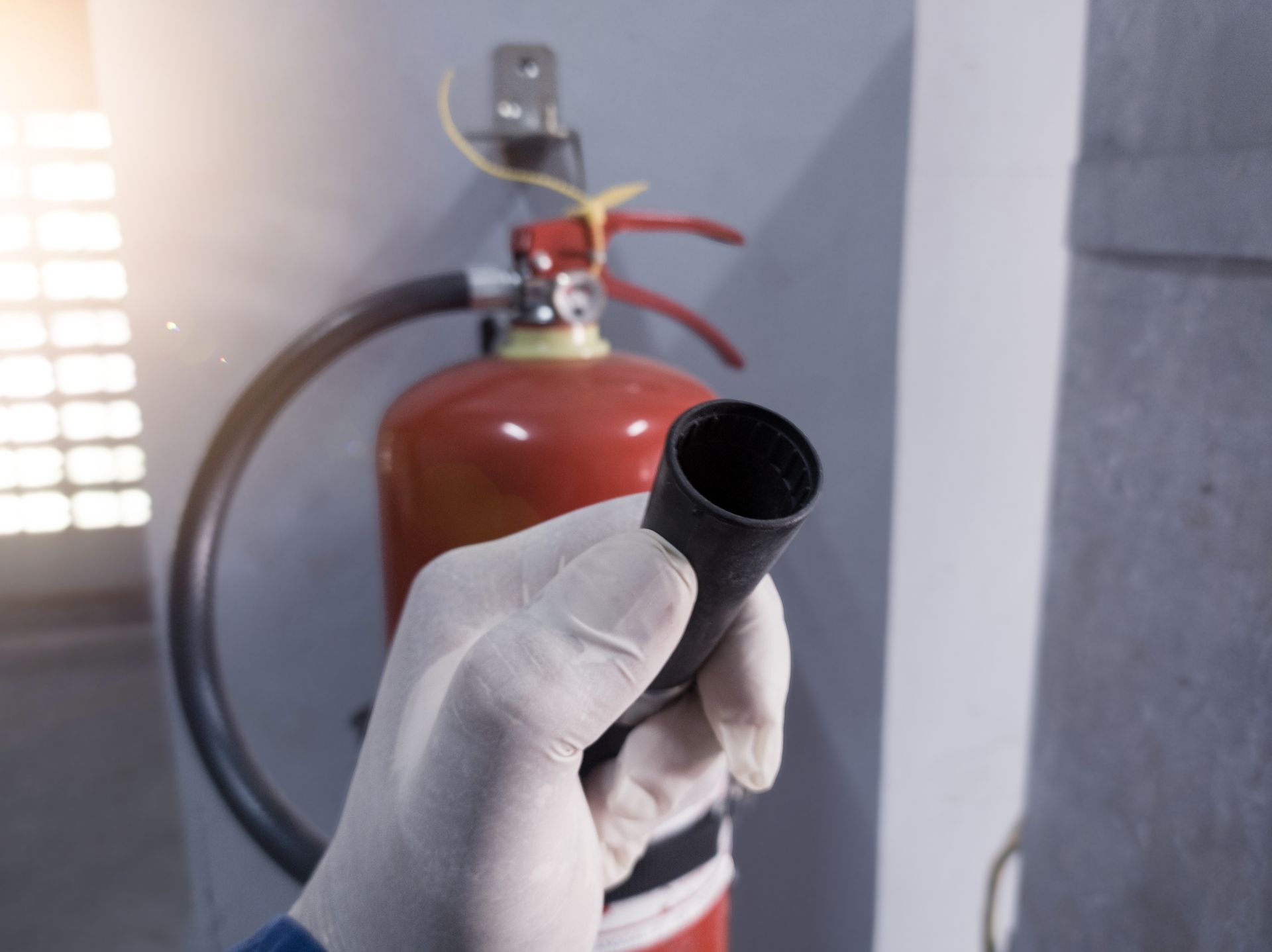 A person is holding a fire extinguisher in front of a fire extinguisher.