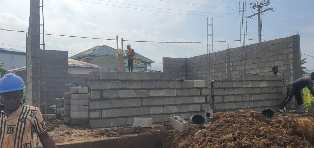 Construction site with workers building a brick wall under a cloudy sky