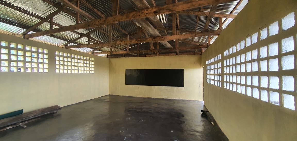 Empty indoor hall with a high wooden roof, glass block walls, and a dark floor