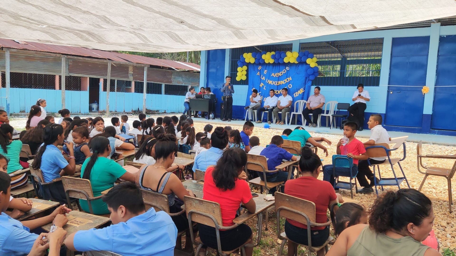 Audience seated under a tent watching a stage performance at an outdoor event
