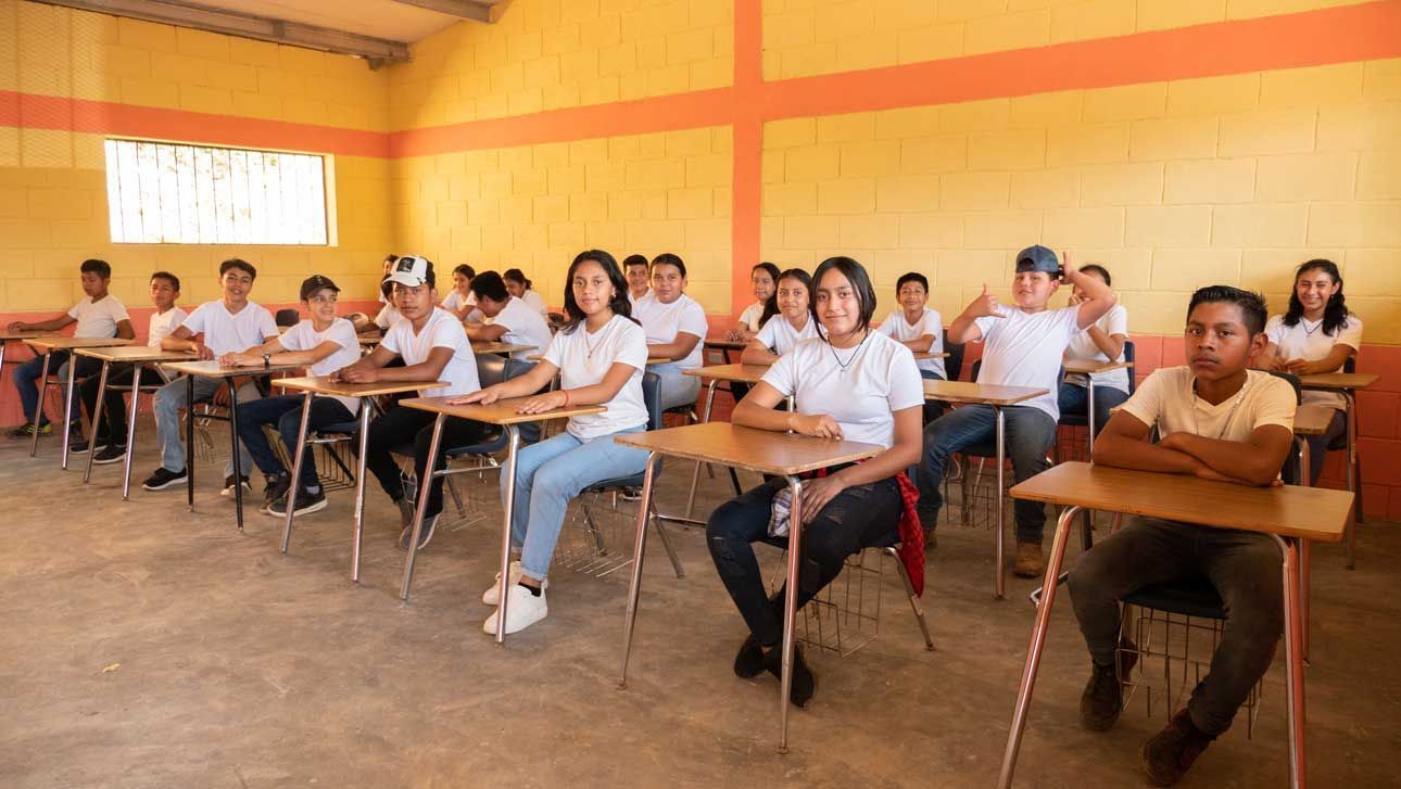 Students seated at desks in a classroom, facing the front during a lesson.