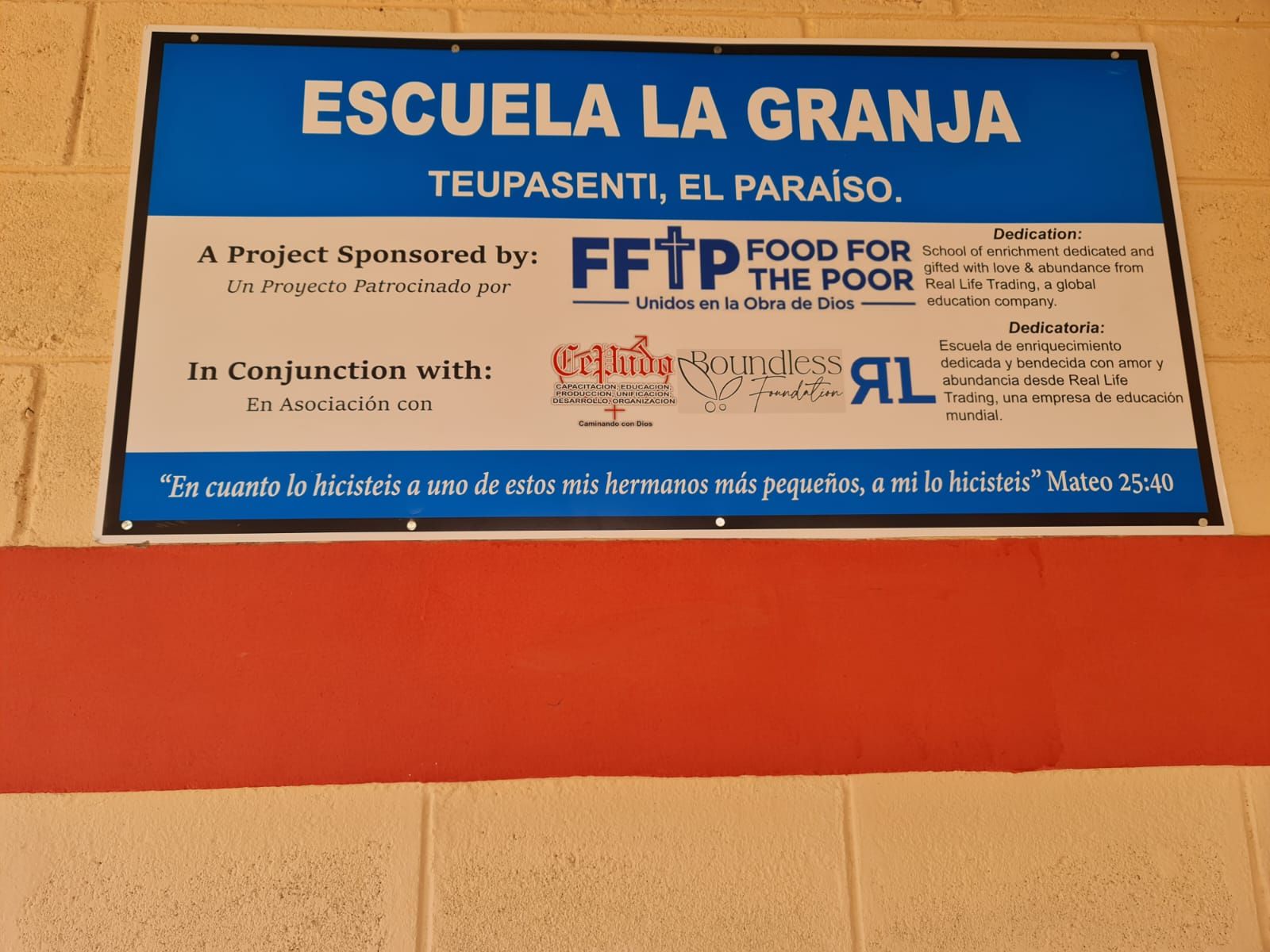 Sign for Escuela La Granja in blue and orange on a stucco wall