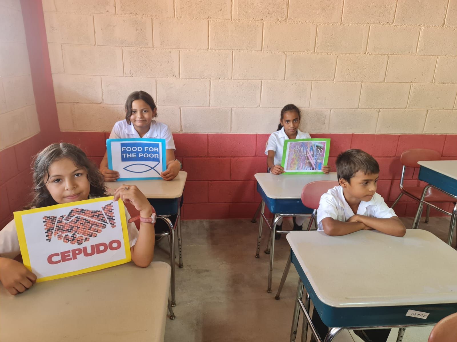 Students seated at classroom desks holding colorful books and learning materials
