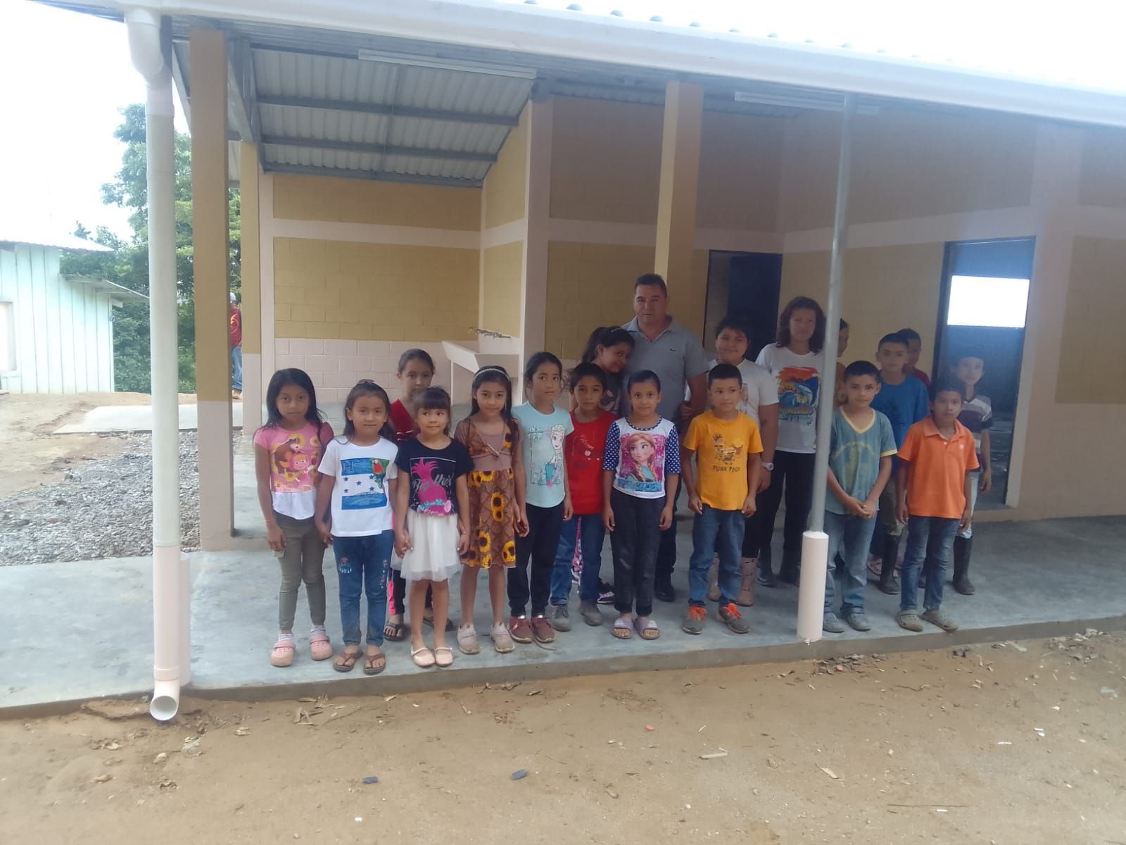 Group of children standing in front of a building porch, posing for a photo.