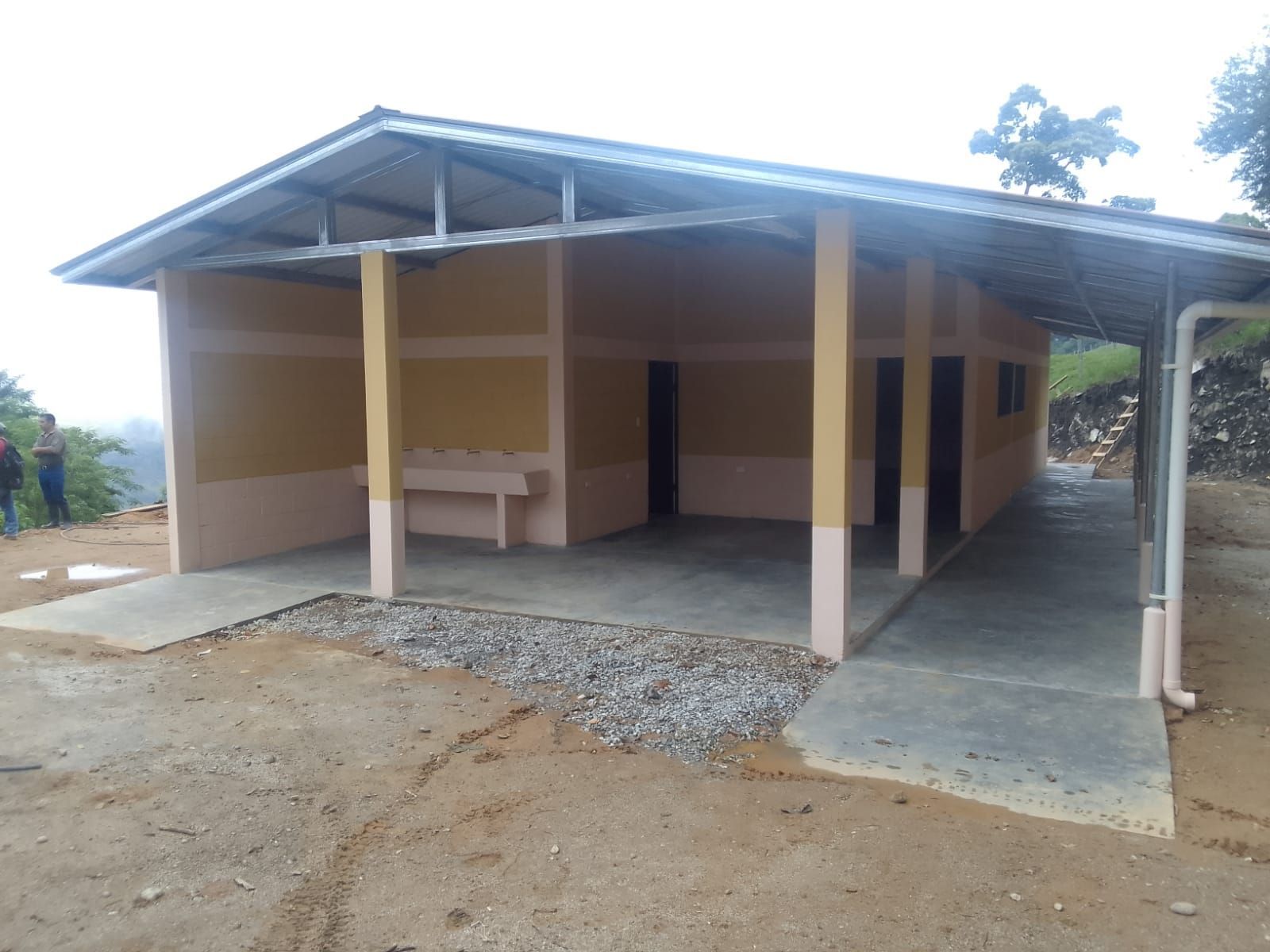 Small rural building with a corrugated metal roof and covered porch on a dirt lot