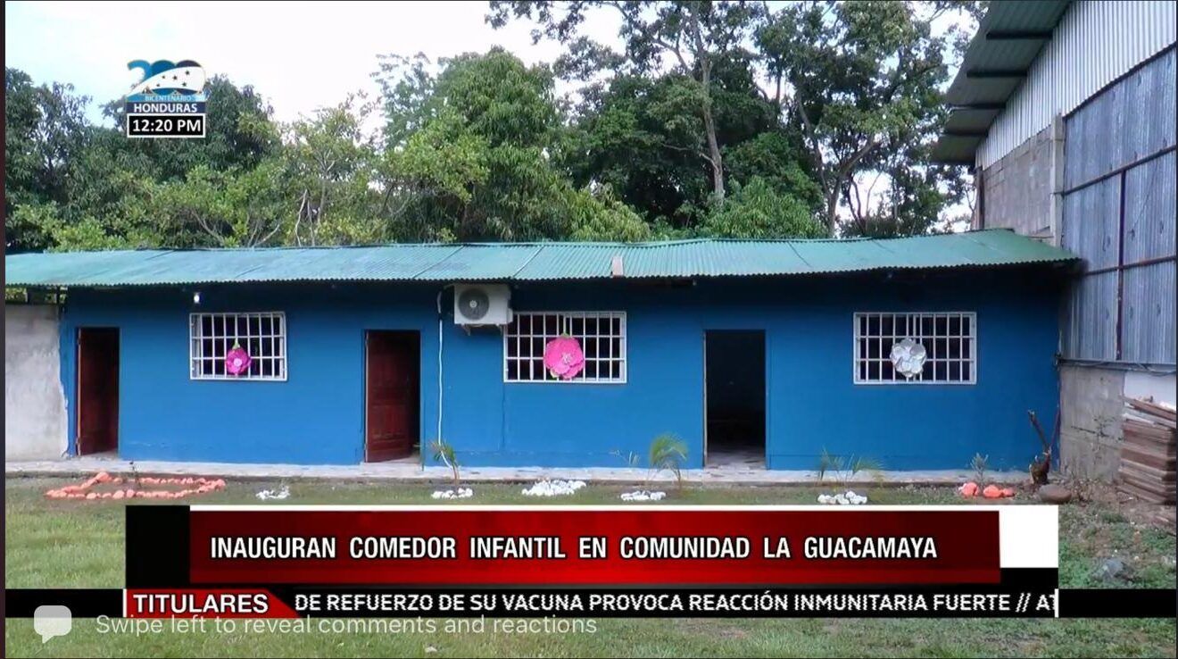 Blue community building with white-trimmed windows and a red news banner at the bottom