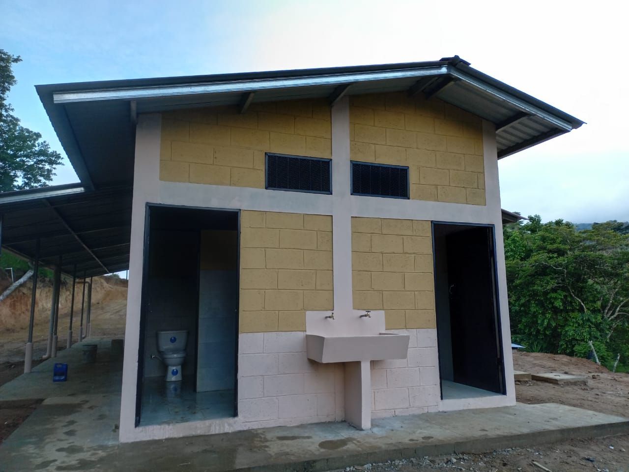 Small two-room outdoor restroom building with yellow and beige walls and open doorways
