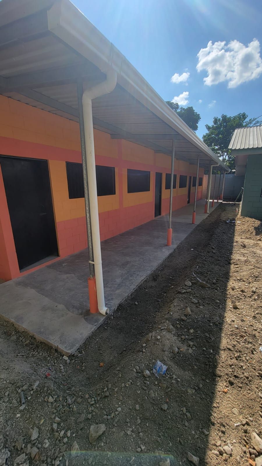 Orange school building with covered walkway and white columns under a bright blue sky