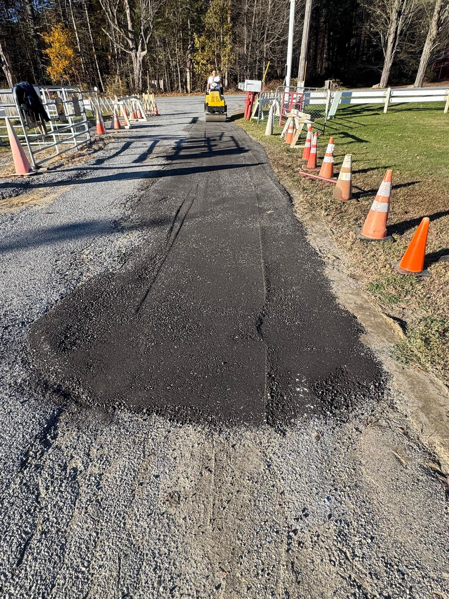 Freshly resurfaced road with orange cones and barriers marking a construction zone